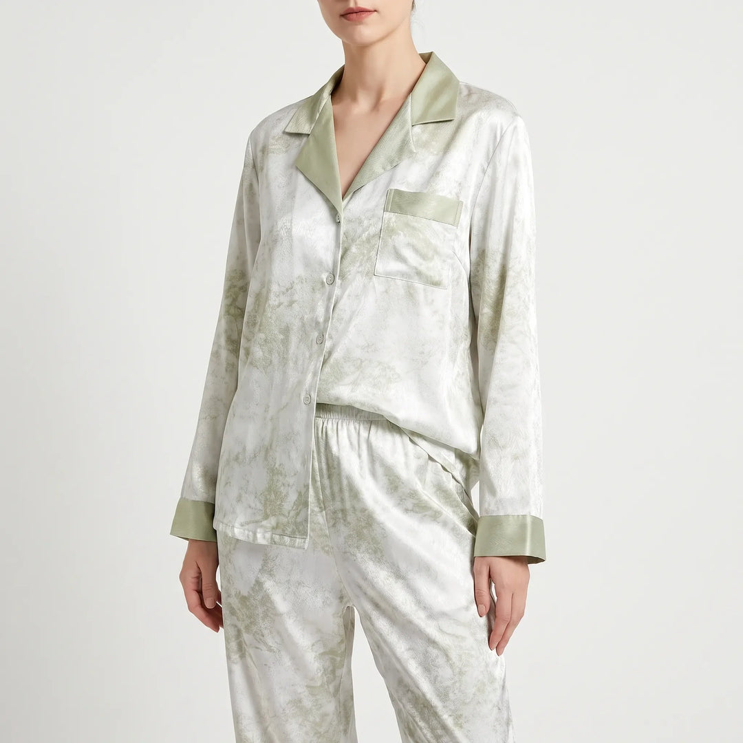 Front three-quarter view of the buttoned pyjama shirt and elastic-waist trousers, white with green marbled print and sage green trim. 2