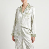Front three-quarter view of the buttoned pyjama shirt and elastic-waist trousers, white with green marbled print and sage green trim. 2