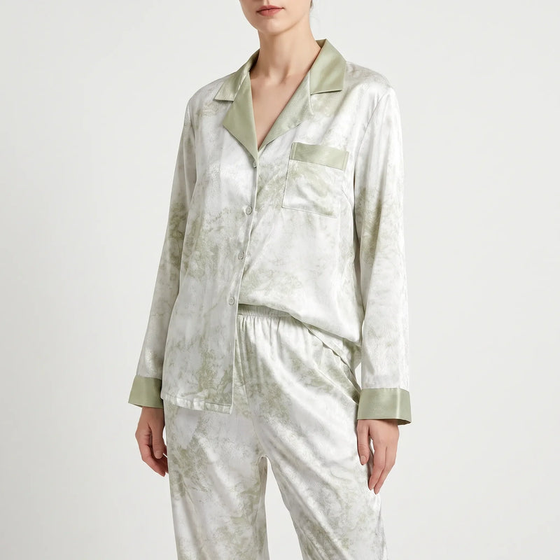 Front three-quarter view of the buttoned pyjama shirt and elastic-waist trousers, white with green marbled print and sage green trim. 2