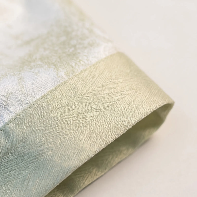Close-up of the sage green cuff, showing its textured weave and stitching against the glossy white printed fabric. 5