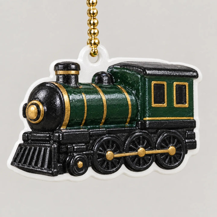 Close-up of a single steam locomotive ornament in green, black and gold with a white outline, hanging from a gold bead chain. 3