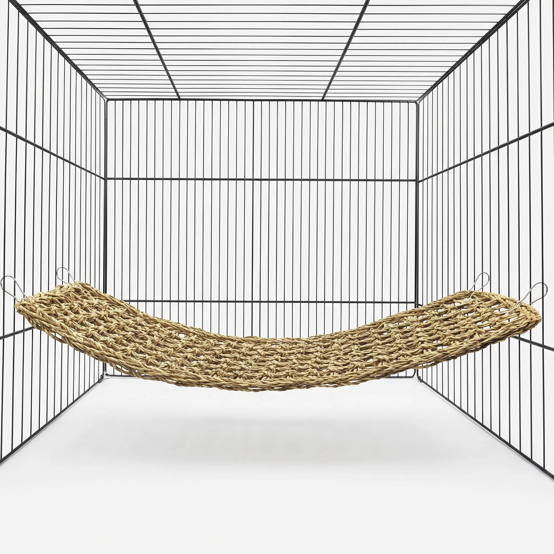 Woven natural-fibre hammock hung by four metal clips inside an empty wire cage, shown against a plain white background. 1