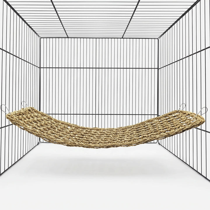 Woven natural-fibre hammock hung by four metal clips inside an empty wire cage, shown against a plain white background. 1