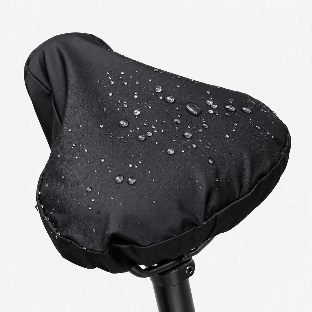 Black saddle cover on a seatpost against a white background, with water droplets beading on the smooth surface. 2