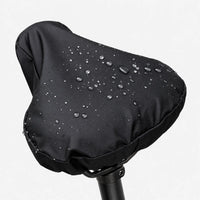 Black saddle cover on a seatpost against a white background, with water droplets beading on the smooth surface. 2