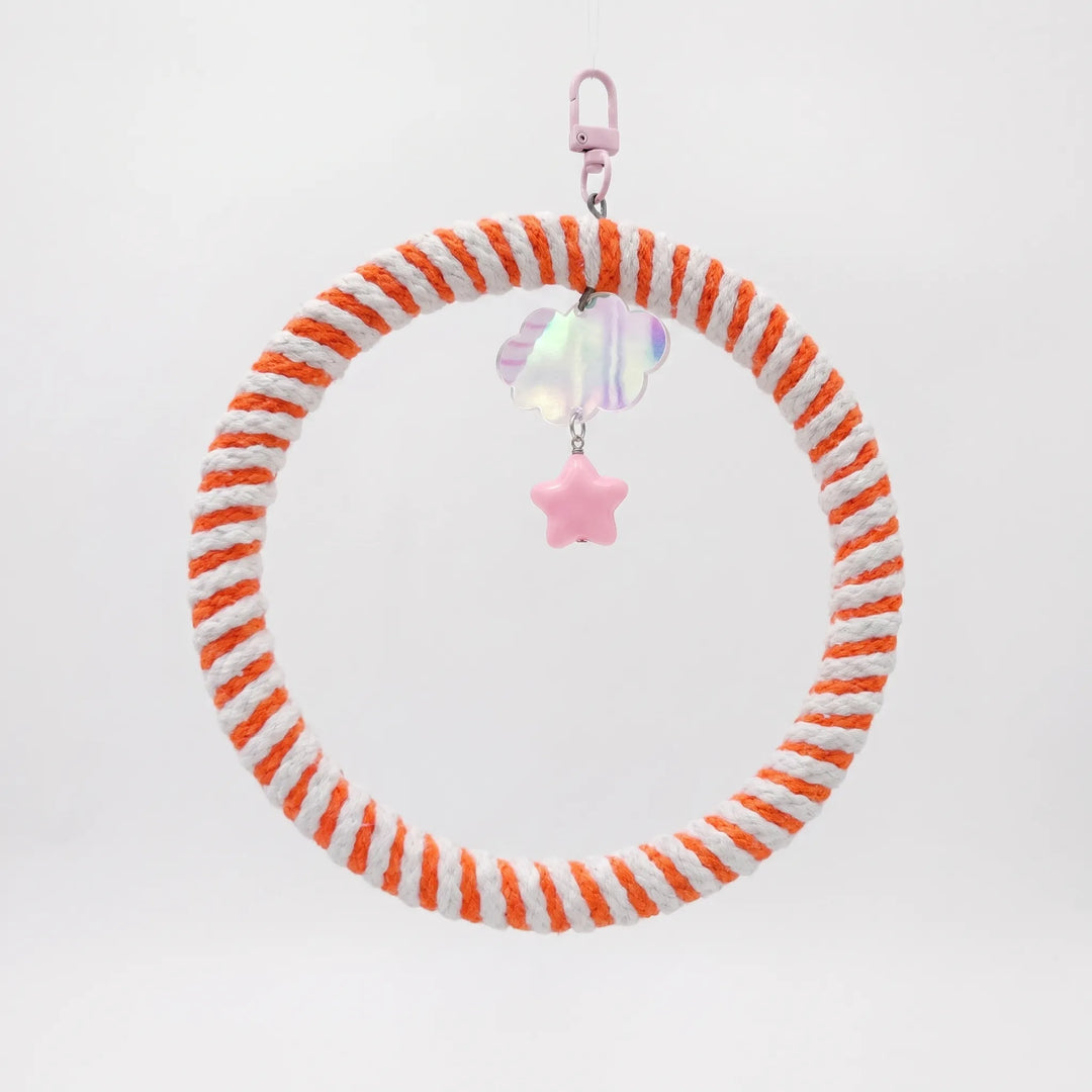 Round swing wrapped in orange and white cotton rope, hanging from a pink clip with an iridescent cloud and pink star charm. 1