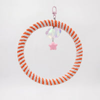 Round swing wrapped in orange and white cotton rope, hanging from a pink clip with an iridescent cloud and pink star charm. 1