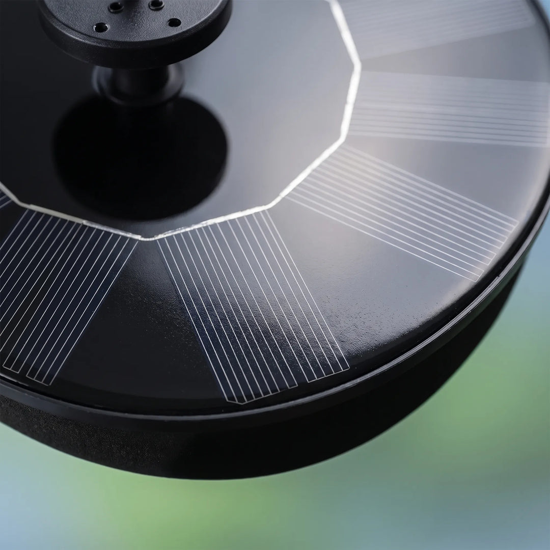 Close-up of the fountain's solar panel surface, showing the fine radiating grid lines, the black nozzle with small holes and the rim. 3