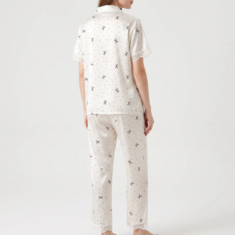 Back view on a model showing the bow and polka dot print across the top and trousers, with lace at sleeves and hems. 3