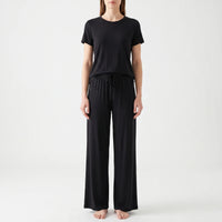 Front view of a model in the black set, with the drawstring tied at the elastic waistband of the trousers. 6