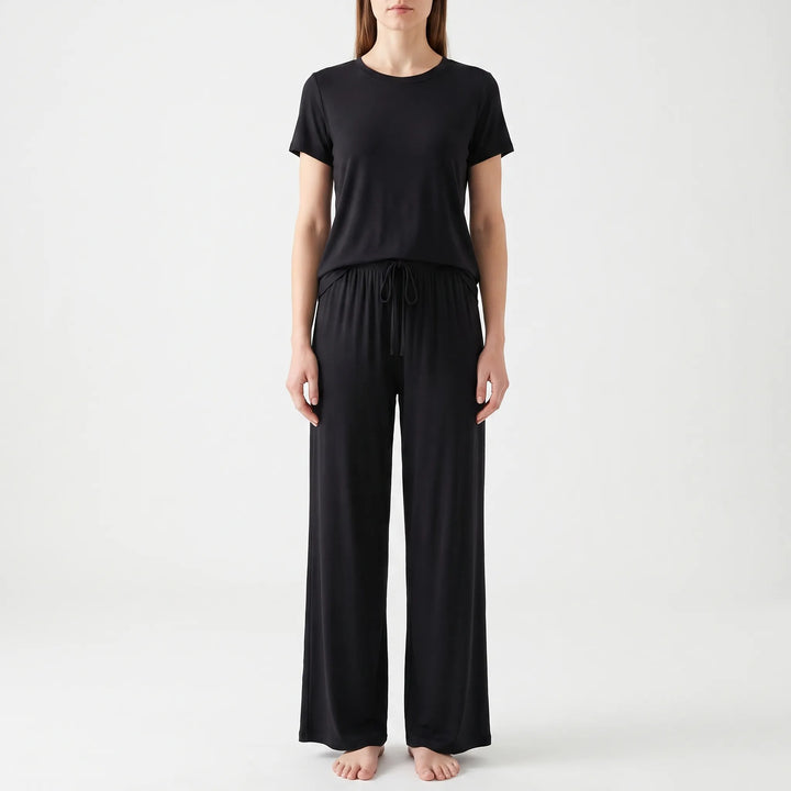 Front view of a model in the black set, with the drawstring tied at the elastic waistband of the trousers. 6