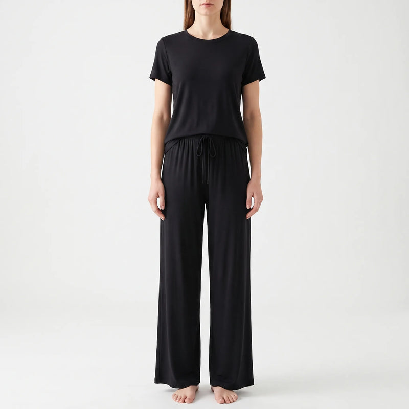 Front view of a model in the black set, with the drawstring tied at the elastic waistband of the trousers. 6
