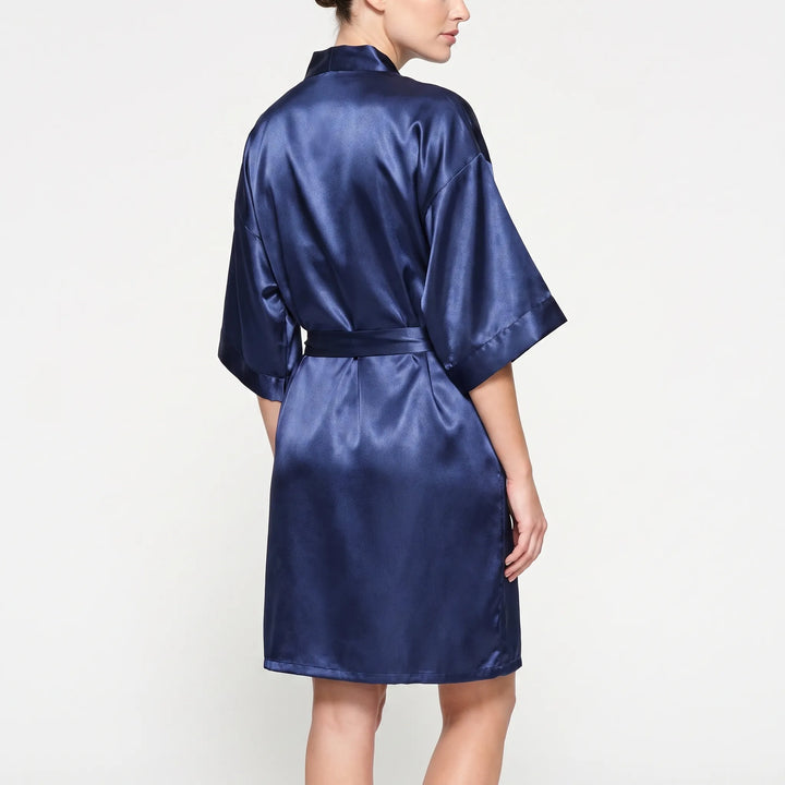 Back view of the navy satin robe on a model, showing the wide kimono sleeves, collar and sash across the waist. 3