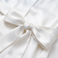 Close-up of the satin belt tied in a bow on the white robe, showing the glossy fabric texture. 5