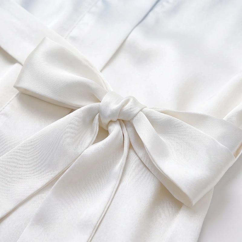 Close-up of the satin belt tied in a bow on the white robe, showing the glossy fabric texture. 5