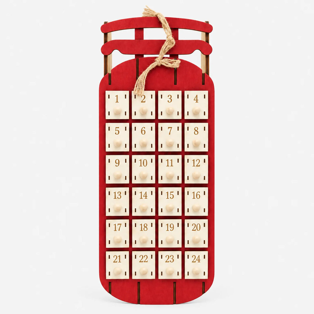 Straight-on view of the red sled advent calendar with 24 numbered cream drawers, wooden knobs and a twine bow on a plain light background. 5