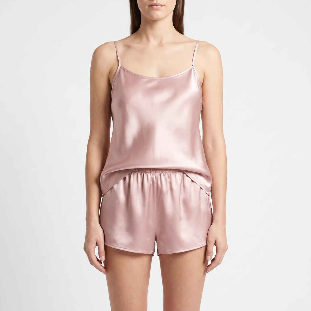 Front view of a model standing in a dusty pink satin camisole with thin straps and elastic-waist shorts. 2