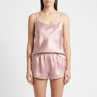 Front view of a model standing in a dusty pink satin camisole with thin straps and elastic-waist shorts. 2