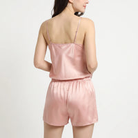 Back view of a model in a pink satin camisole with adjustable straps and gathered elastic-waist shorts. 3