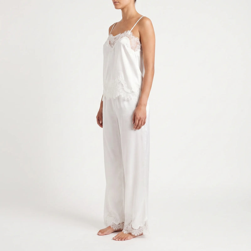 Side view of a model in the white satin set, showing the lace-trimmed camisole neckline and hem and the lace-edged trouser cuffs. 4