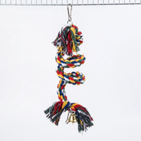 Multicoloured twisted cotton rope spiral with frayed ends, a gold bell and a metal clip, hanging from a wire cage roof against white. 1