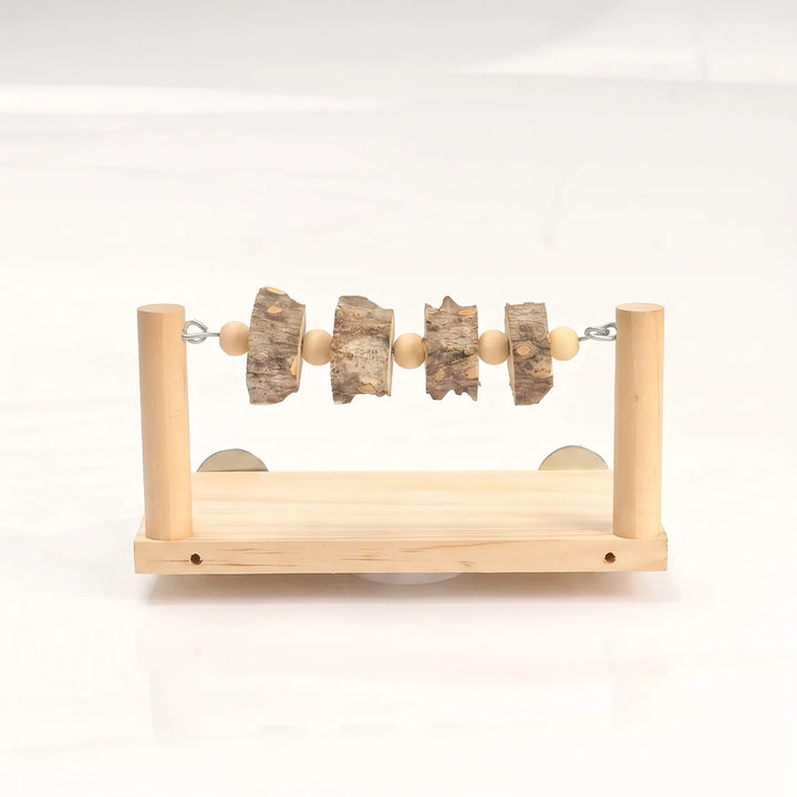 Front view of a wooden perch platform with two upright posts, a bar strung with wooden beads and bark slices, and metal discs behind. 1