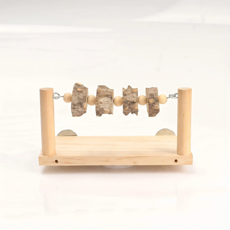 Front view of a wooden perch platform with two upright posts, a bar strung with wooden beads and bark slices, and metal discs behind. 1
