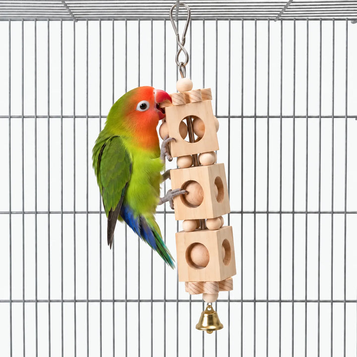 Lovebird climbing and nibbling the hanging wooden block toy with its round holes, beads and brass bell inside a wire cage. 1