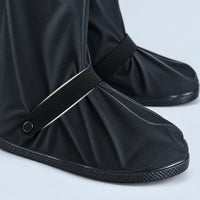 Close-up of the black shoe cover toe area showing the elastic ankle strap with snap button and textured rubber sole. 6