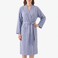 Front view of a model in the blue waffle-weave robe with belt tied, one hand on hip, patch pockets visible. 2