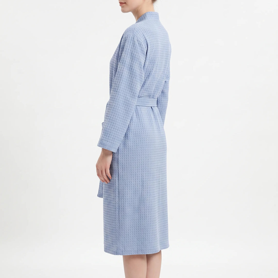 Side view of the blue waffle robe on a model, showing the long sleeve, belt and knee-length hem. 4