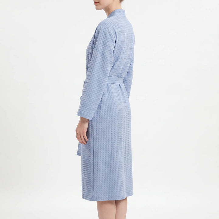 Side view of the blue waffle robe on a model, showing the long sleeve, belt and knee-length hem. 4