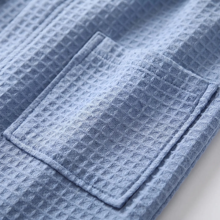 Close-up of the blue waffle-weave fabric and a stitched patch pocket, showing the raised grid texture. 5