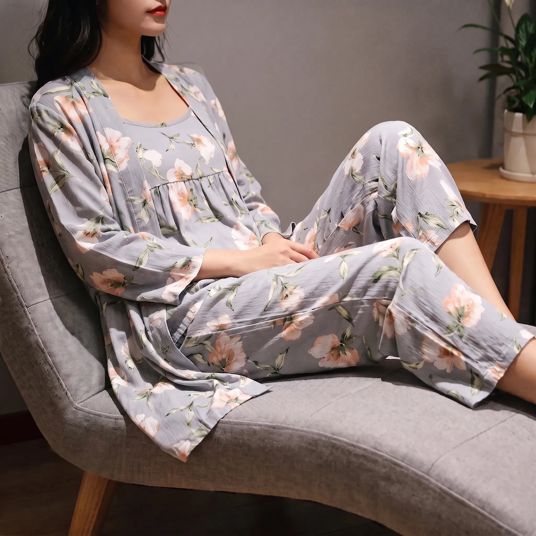 Model reclining on a grey armchair in the grey floral robe, camisole and trousers, hands resting in her lap. 1