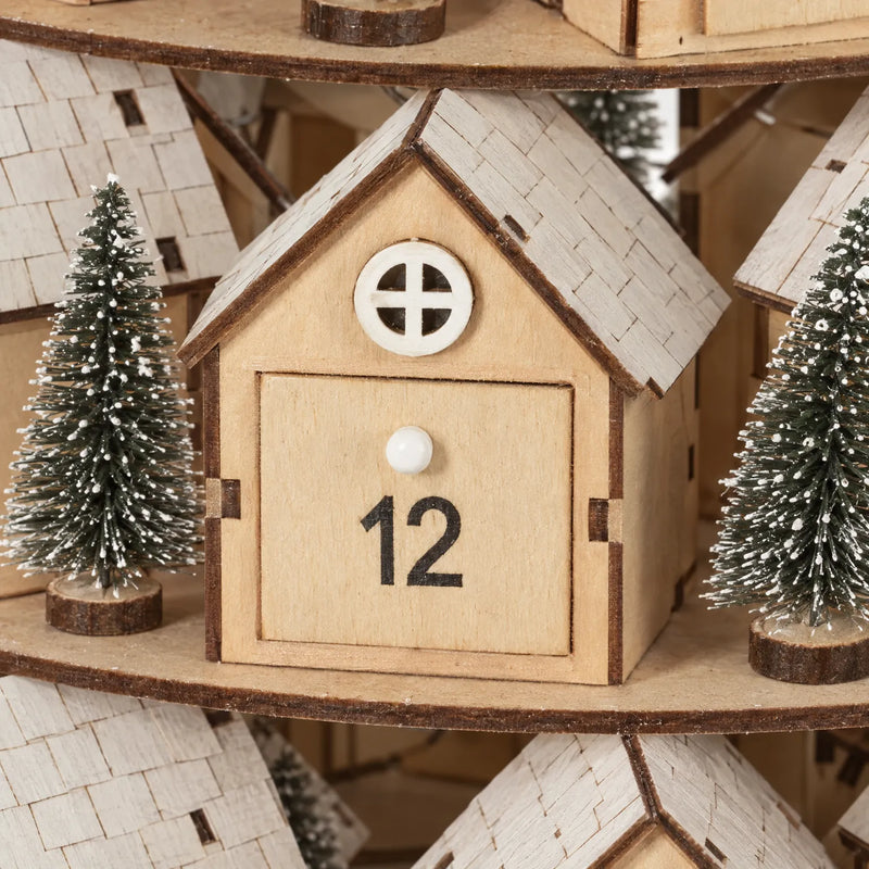 Close-up of one wooden house with a numbered sliding drawer, white knob, round window, shingled roof and flanking frosted mini trees. 3