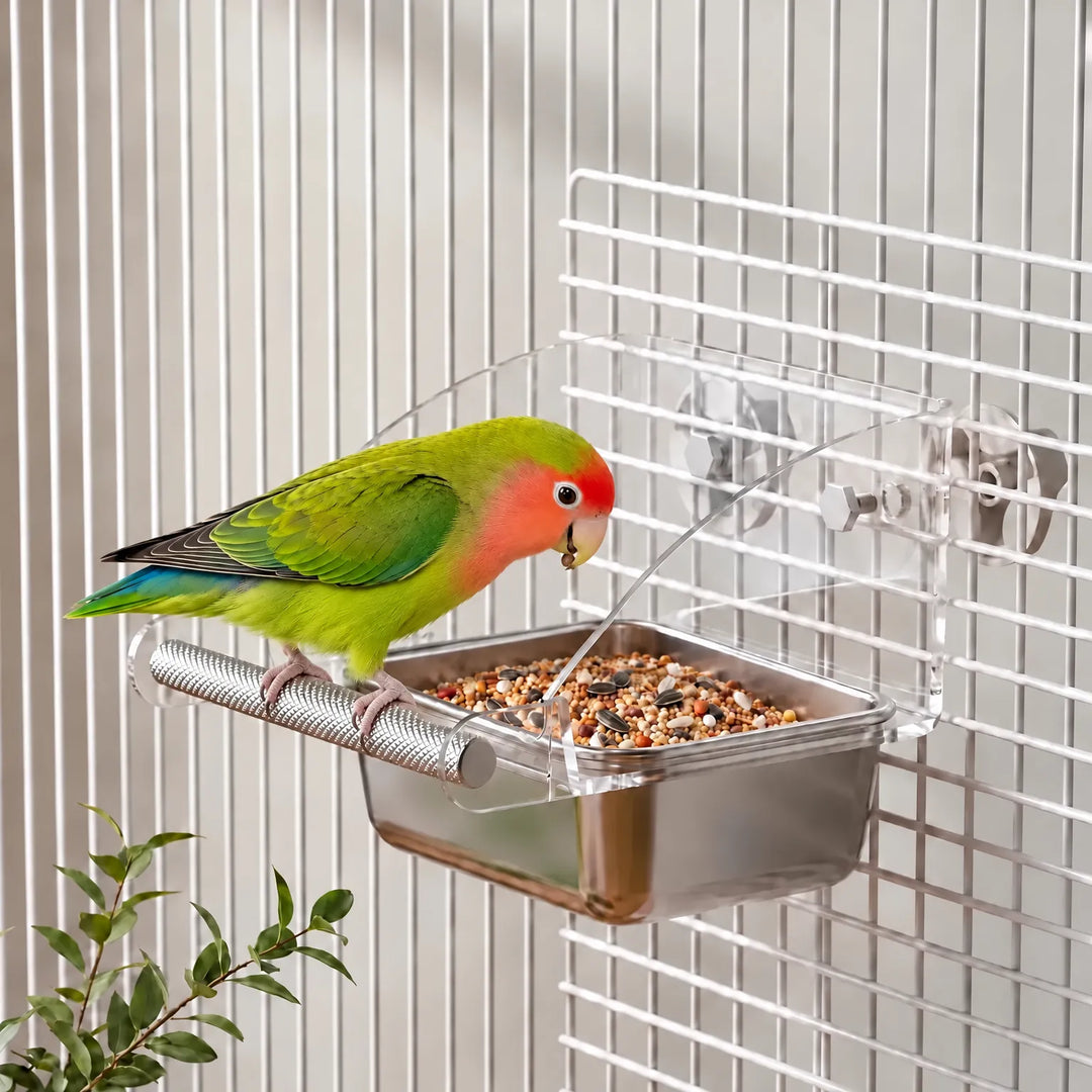A green lovebird with a red face perches on the feeder, which is fixed to a cage and filled with seed. 2