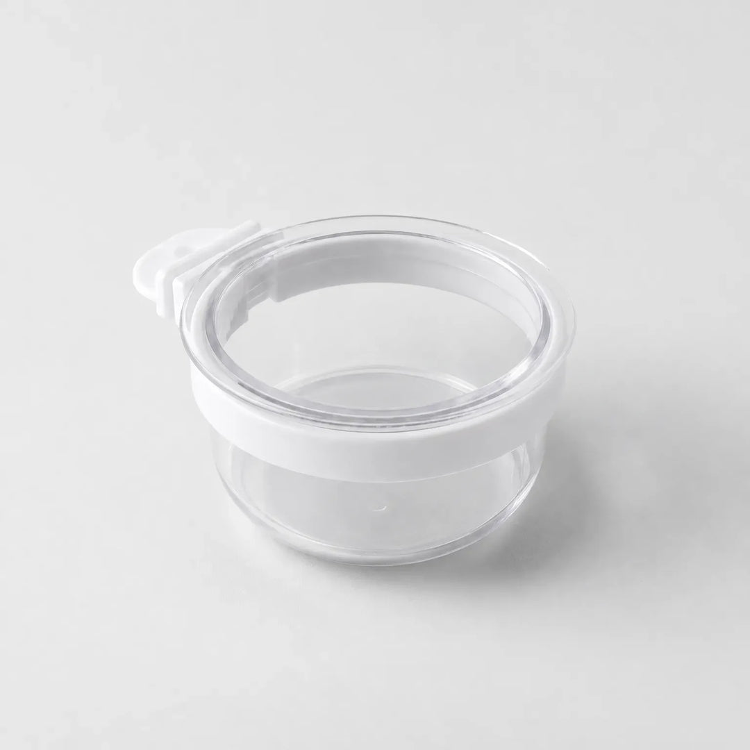 Empty clear plastic bowl with a white rim band and a small white hook tab on one side, shown on a plain grey background. 1