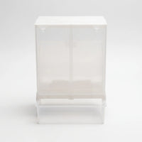Front view of the clear plastic seed dispenser with its white lid and pull-out tray beneath, shown empty on a plain background. 1
