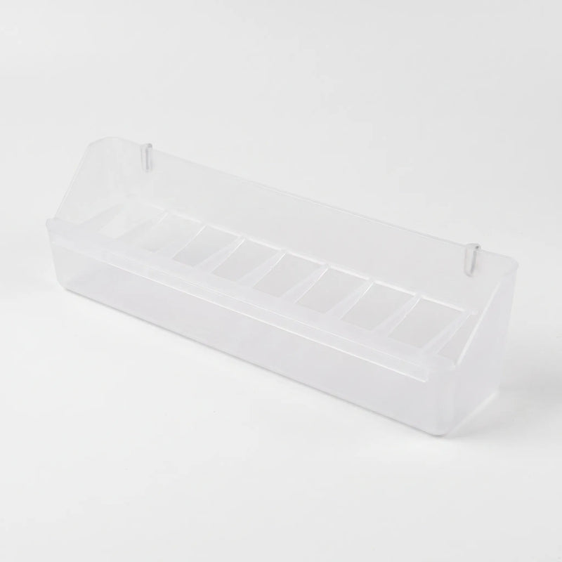 Angled view of the empty long clear feeder showing its row of small compartments and two hanging pegs. 7