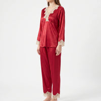 Three-quarter side view of a model wearing the red satin pyjama set with cream lace on neckline, cuffs and ankle hems. 4