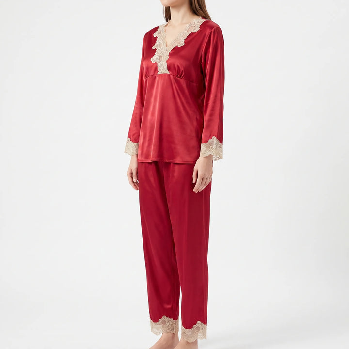 Three-quarter side view of a model wearing the red satin pyjama set with cream lace on neckline, cuffs and ankle hems. 4