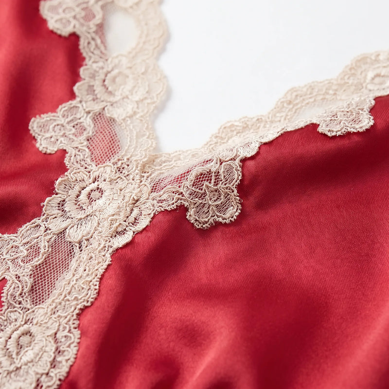 Macro detail of the cream floral lace edging along the V-neckline of the red satin pyjama top. 5
