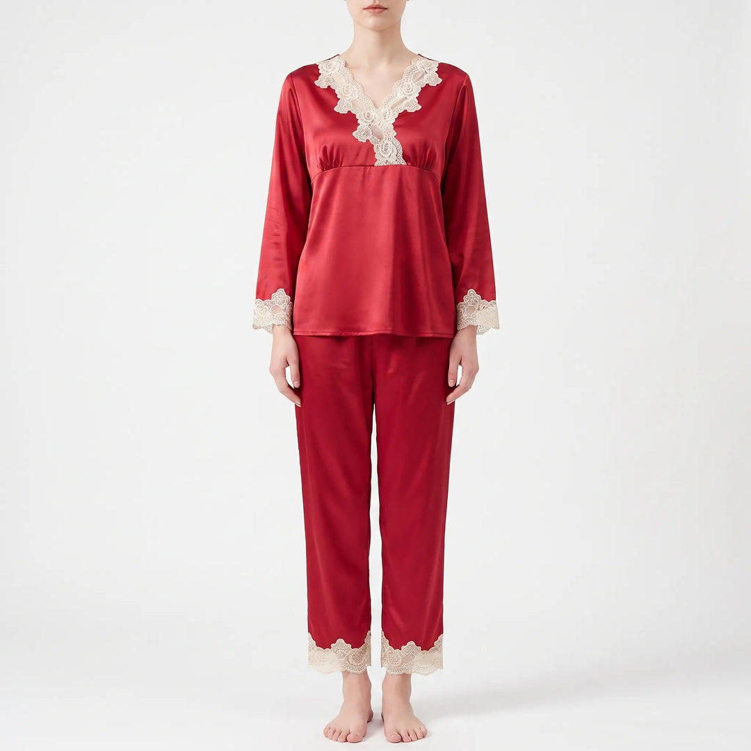 Full-length front view of a model standing barefoot in the red satin pyjama set with lace-trimmed cuffs and trouser hems. 6