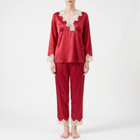 Full-length front view of a model standing barefoot in the red satin pyjama set with lace-trimmed cuffs and trouser hems. 6