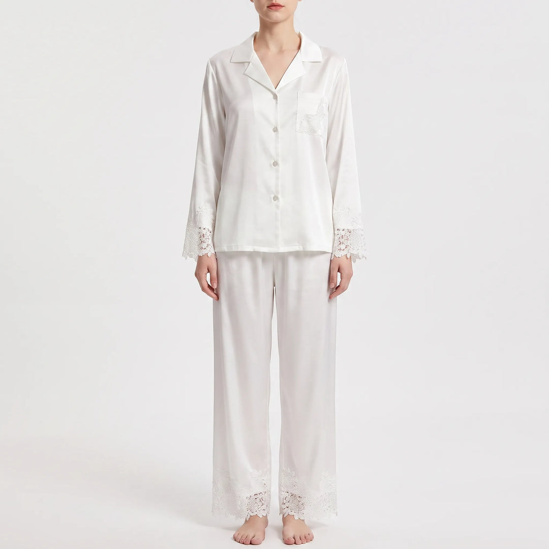 Straight-on front view of the white pajama set worn by a model with arms relaxed, lace on cuffs, pocket and trouser hems. 6