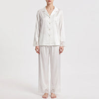 Straight-on front view of the white pajama set worn by a model with arms relaxed, lace on cuffs, pocket and trouser hems. 6