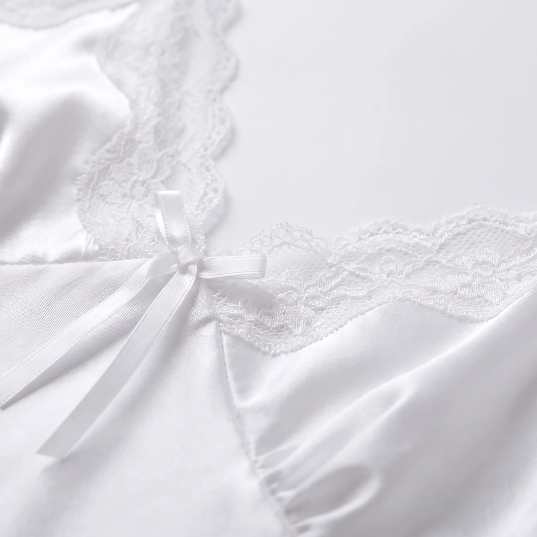 Close-up detail of the white satin bodice with scalloped lace edging and a small satin bow at the centre of the V-neck. 5