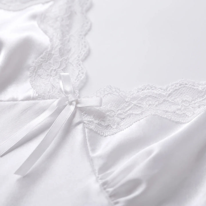 Close-up detail of the white satin bodice with scalloped lace edging and a small satin bow at the centre of the V-neck. 5