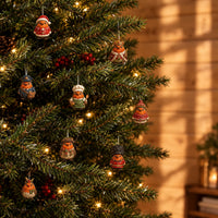 Small robin figurines in festive costumes, including a king, a chef and a postman, hanging from a lit Christmas tree. 1