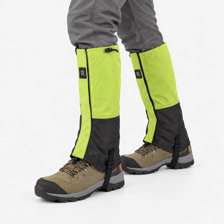 Lime green and black gaiters with drawcord tops worn over brown hiking boots, shown mid-stride against a white background. 4